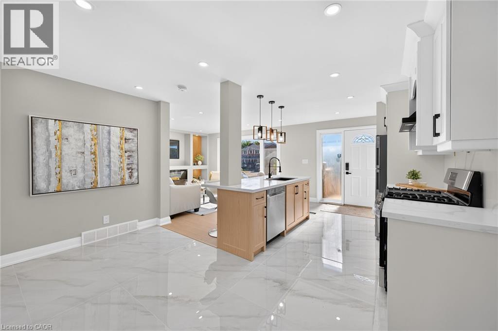 Open concept design with recessed lighting, tile flooring, kitchen island, white cabinetry, and stainless steel appliances - 135 Nugent Drive, Hamilton, ON
