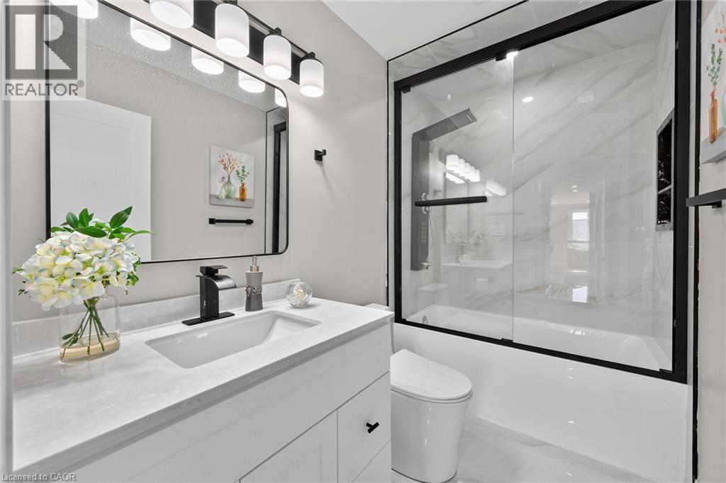 White vanity with integrated sink, black-framed mirror, and matte black fixtures - 135 Nugent Drive, Hamilton, ON