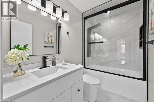 White vanity with integrated sink, black-framed mirror, and matte black fixtures - 135 Nugent Drive, Hamilton, ON 