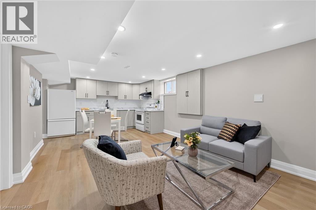 Open-concept living area featuring wood-finish flooring, recessed lighting, a compact kitchen with light-toned cabinetry, and a dining area - 135 Nugent Drive, Hamilton, ON