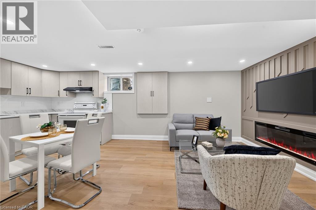 Wood-finish flooring, recessed lighting, built-in electric fireplace, light-toned cabinetry, and a window - 135 Nugent Drive, Hamilton, ON