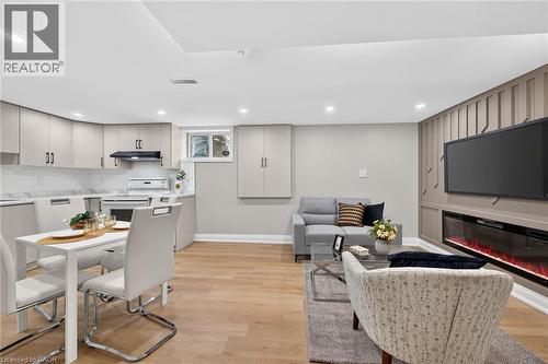 Wood-finish flooring, recessed lighting, built-in electric fireplace, light-toned cabinetry, and a window - 135 Nugent Drive, Hamilton, ON 