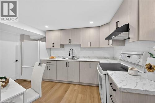 Contemporary kitchen featuring light wood-finish cabinetry, white countertops, white subway tile backsplash, recessed lighting, and wood-finish flooring - 135 Nugent Drive, Hamilton, ON 