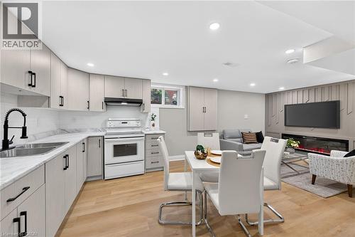 Full kitchen with light-toned cabinetry, white appliances, and a black gooseneck faucet - 135 Nugent Drive, Hamilton, ON 