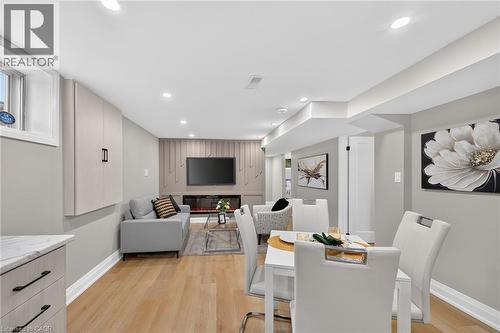 Recessed lighting, wood-finish flooring, built-in wall cabinetry, built-in electric fireplace, and a dining area with a white table - 135 Nugent Drive, Hamilton, ON 