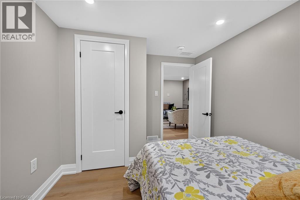 Light wood-finish flooring, recessed lighting, white doors with matte black hardware, and neutral gray wall paint - 135 Nugent Drive, Hamilton, ON