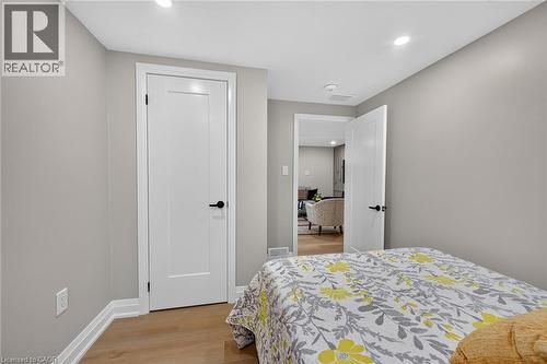Light wood-finish flooring, recessed lighting, white doors with matte black hardware, and neutral gray wall paint - 135 Nugent Drive, Hamilton, ON 