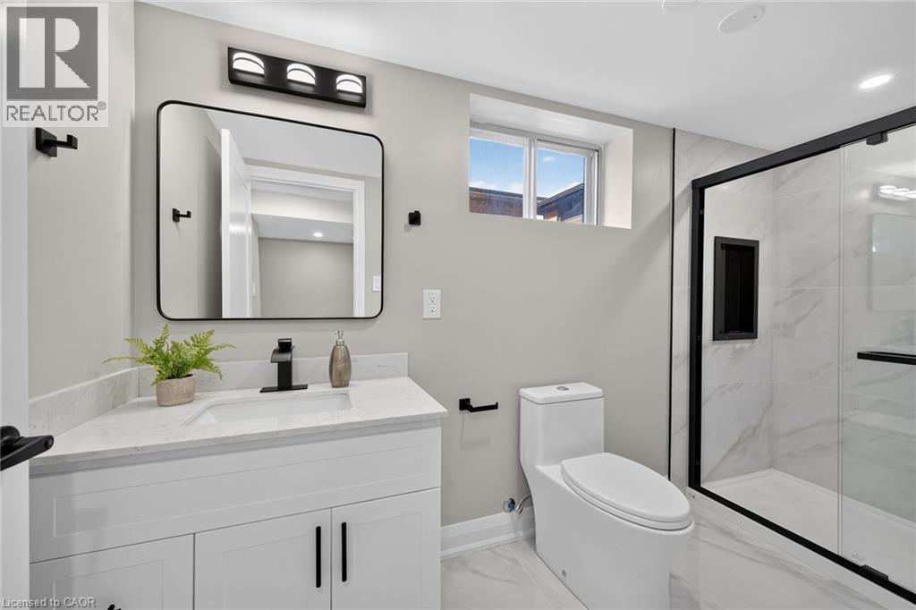 White vanity with a light-toned countertop, black framed mirror, and matte black fixtures - 135 Nugent Drive, Hamilton, ON