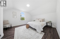 White painted walls with vaulted ceilings, wood-finish flooring, and an arched window - 