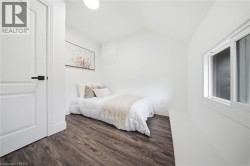 Bright room featuring wood-finish flooring, a white paneled door with matte black hardware, and a sliding window - 