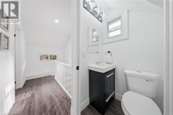 Powder room featuring a single vanity with dark cabinetry, a wall-mounted mirror, and a toilet - 