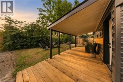 Expansive backyard featuring a covered wood deck, shingled exterior, and established perimeter landscaping - 