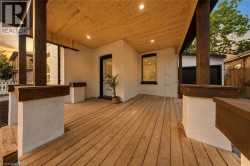 Expansive covered porch featuring wood-finish decking, exposed wood-finish ceiling with recessed lighting, and substantial wood-finish support columns - 