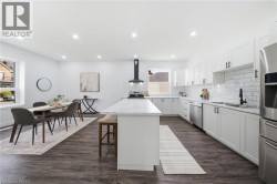 Open-concept kitchen and dining area featuring recessed lighting, extensive white cabinetry, an island with a countertop, stainless steel appliances, and wood-finish flooring - 