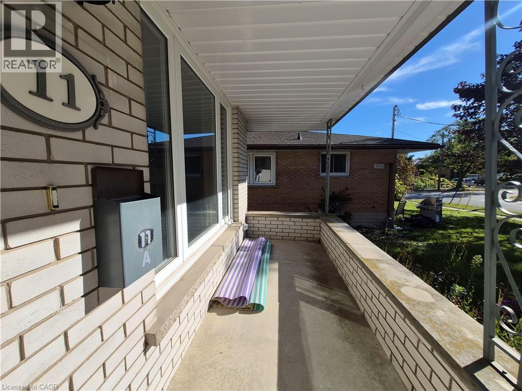 Covered front porch with brick siding, a concrete floor, and a decorative metal railing - 11 Duncairn Avenue, Kitchener, ON
