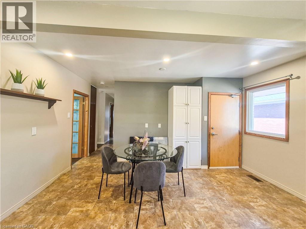 Recessed lighting illuminates the open-concept space featuring a built-in white cabinet unit and wood-finish flooring throughout - 11 Duncairn Avenue, Kitchener, ON