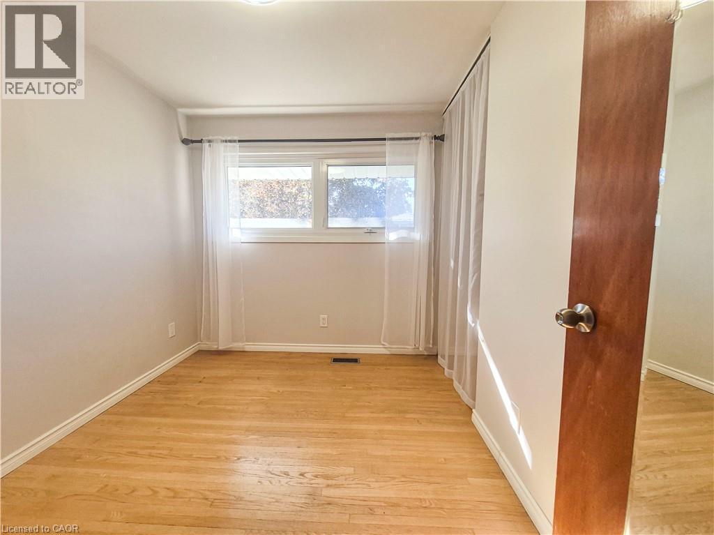 Wood-finish flooring, white trim, and a window with a curtain rod - 11 Duncairn Avenue, Kitchener, ON