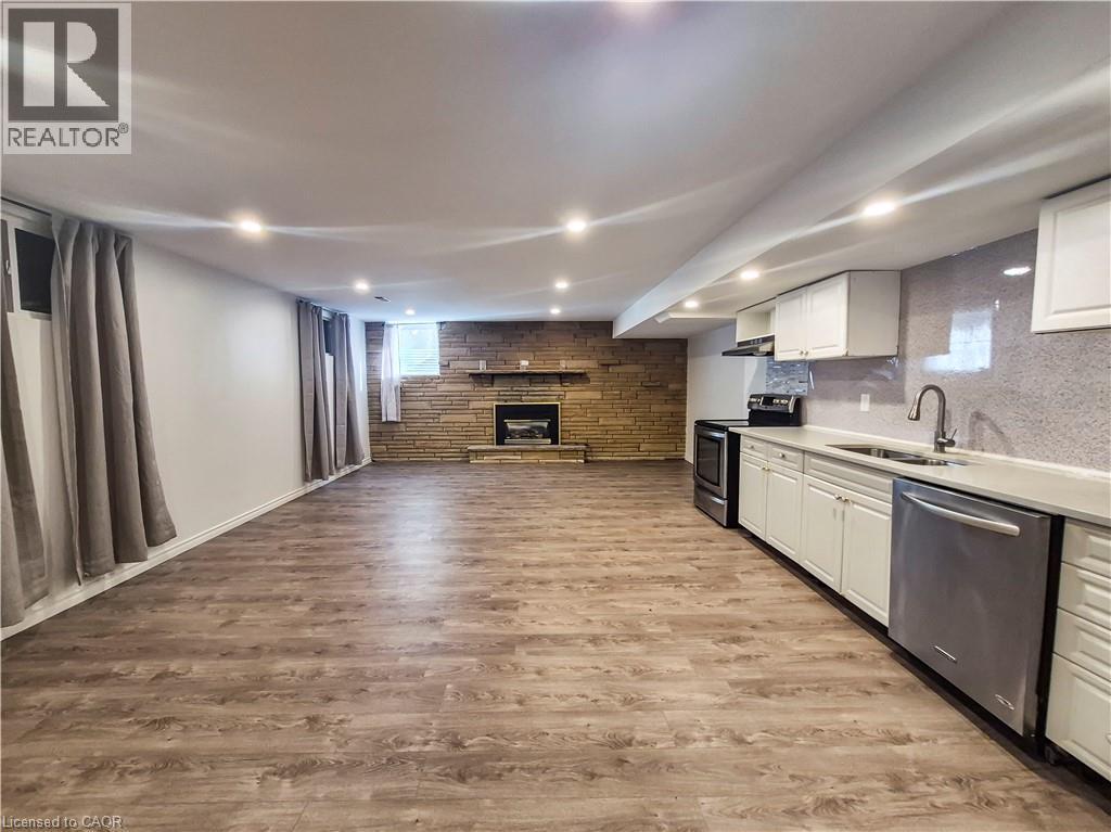 Spacious open concept room featuring wood-finish flooring, recessed lighting, and a stone-clad fireplace - 11 Duncairn Avenue, Kitchener, ON
