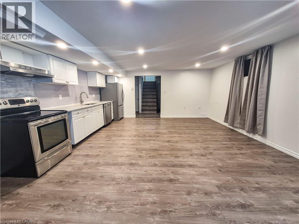 Open-concept living space with wood-finish flooring, recessed lighting, and a full kitchen - 11 Duncairn Avenue, Kitchener, ON