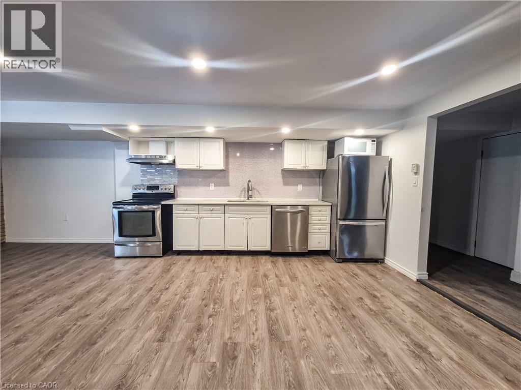 Open-concept kitchen with wood-finish flooring, white cabinetry, stainless steel appliances, and recessed lighting - 11 Duncairn Avenue, Kitchener, ON