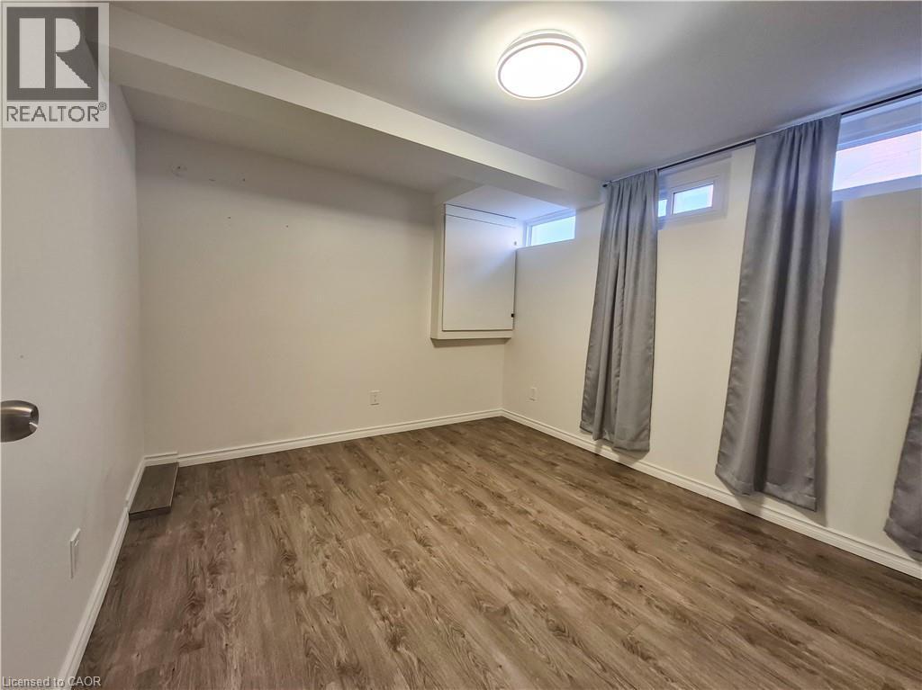 Wood-finish flooring, white baseboards, and ceiling-mounted light fixture - 11 Duncairn Avenue, Kitchener, ON