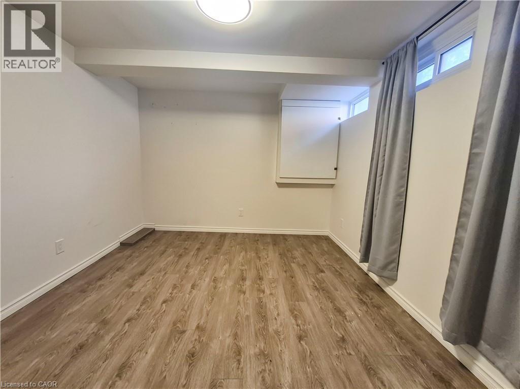 Wood-finish flooring, white walls, and an overhead flush-mount light fixture - 11 Duncairn Avenue, Kitchener, ON