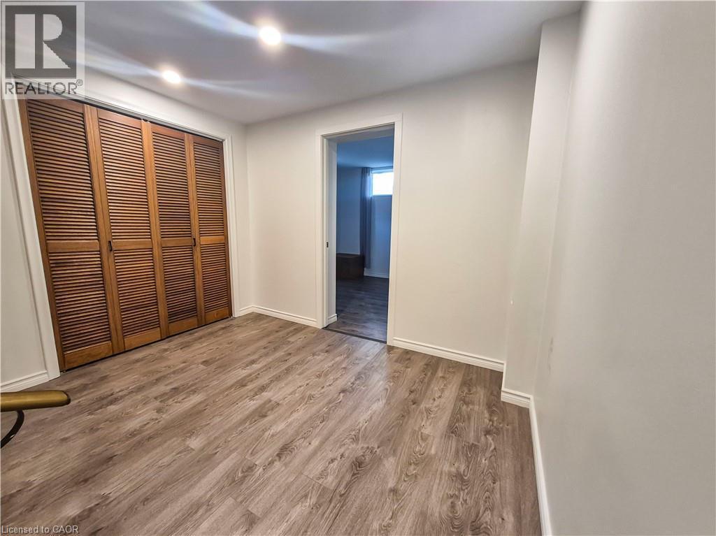 Wood-finish flooring, recessed ceiling lighting, louvered bi-fold closet doors, and white painted walls - 11 Duncairn Avenue, Kitchener, ON