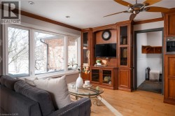 Hardwood flooring, expansive built-in cabinetry with glass-front uppers, recessed lighting, and a ceiling fan with light fixture - 