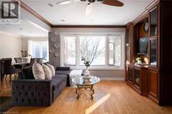 Hardwood flooring, crown molding, built-in media cabinetry, recessed lighting, and a large multi-pane window - 