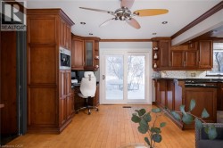 Hardwood flooring, wood-finish cabinetry, built-in coffee maker, recessed lighting, and a ceiling fan - 