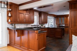 Rich wood cabinetry, black countertops, tile backsplash, recessed lighting, and a kitchen island - 