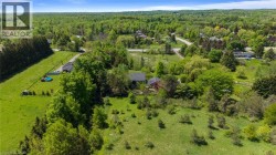 Expansive property with a dwelling featuring a dark roof, surrounded by mature trees and lush green landscaping - 