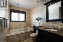 Built-in soaking tub with deck-mounted faucet, stone-finish tile surround, and recessed lighting - 