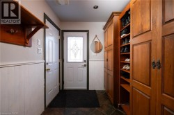Entryway featuring wood-finish flooring, white wainscoting, and built-in wood cabinetry with integrated shelving - 