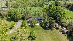 Property set amidst expansive green landscape, featuring a winding driveway, mature trees, and a separate outbuilding - 