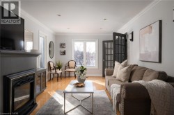 Hardwood-style flooring, a recessed fireplace with mantel, crown molding, double French doors, and recessed lighting - 