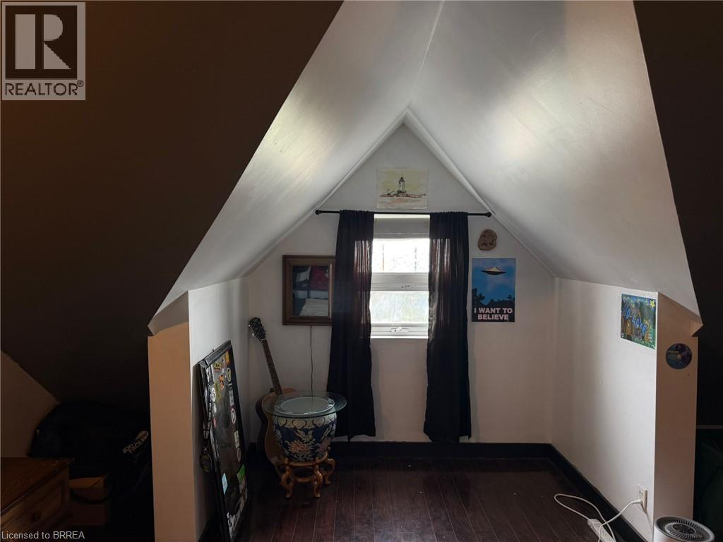 Attic space with sloped ceilings, a centered window, and dark wood-finish flooring - 12 Bridgeport Road E Unit# 18, Waterloo, ON