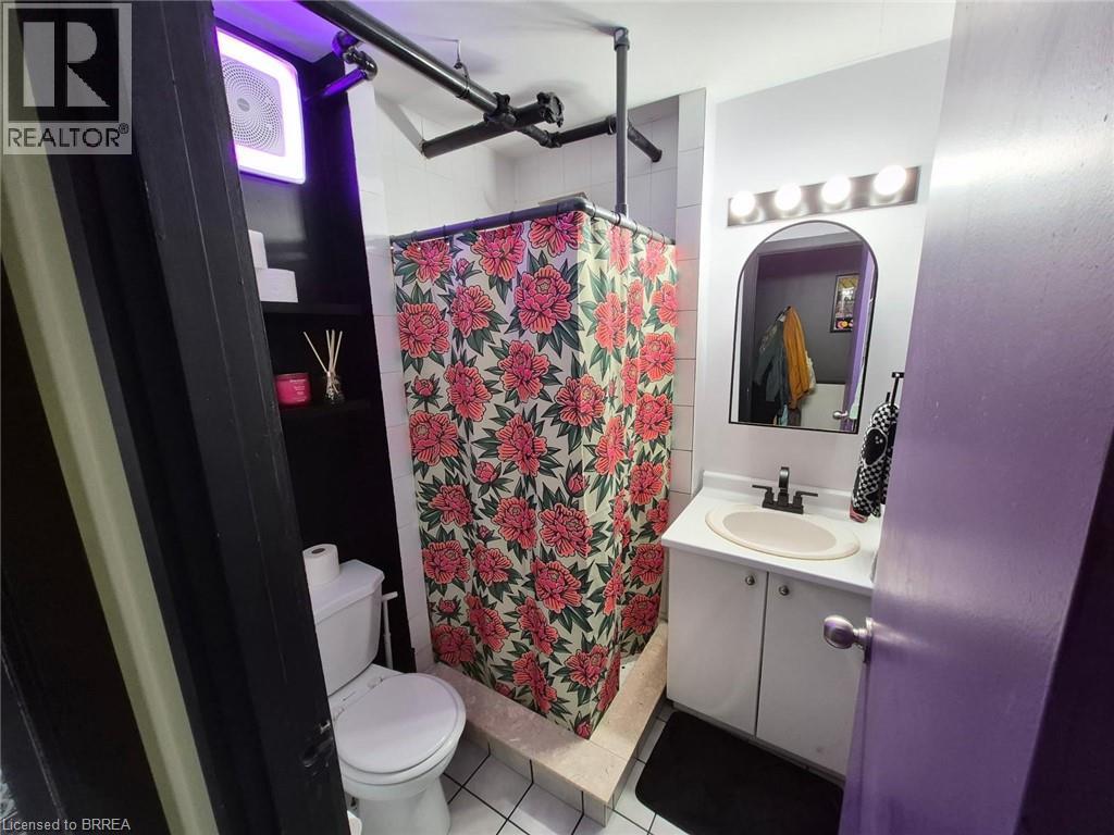 Tiled shower stall with pipe-style enclosure, vanity with basin sink, and built-in shelving - 12 Bridgeport Road E Unit# 18, Waterloo, ON