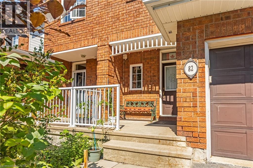 Brick exterior with a covered porch, white railing, concrete steps, and a dark wood entry door - 82 Milner Downs Crescent, Ottawa, ON