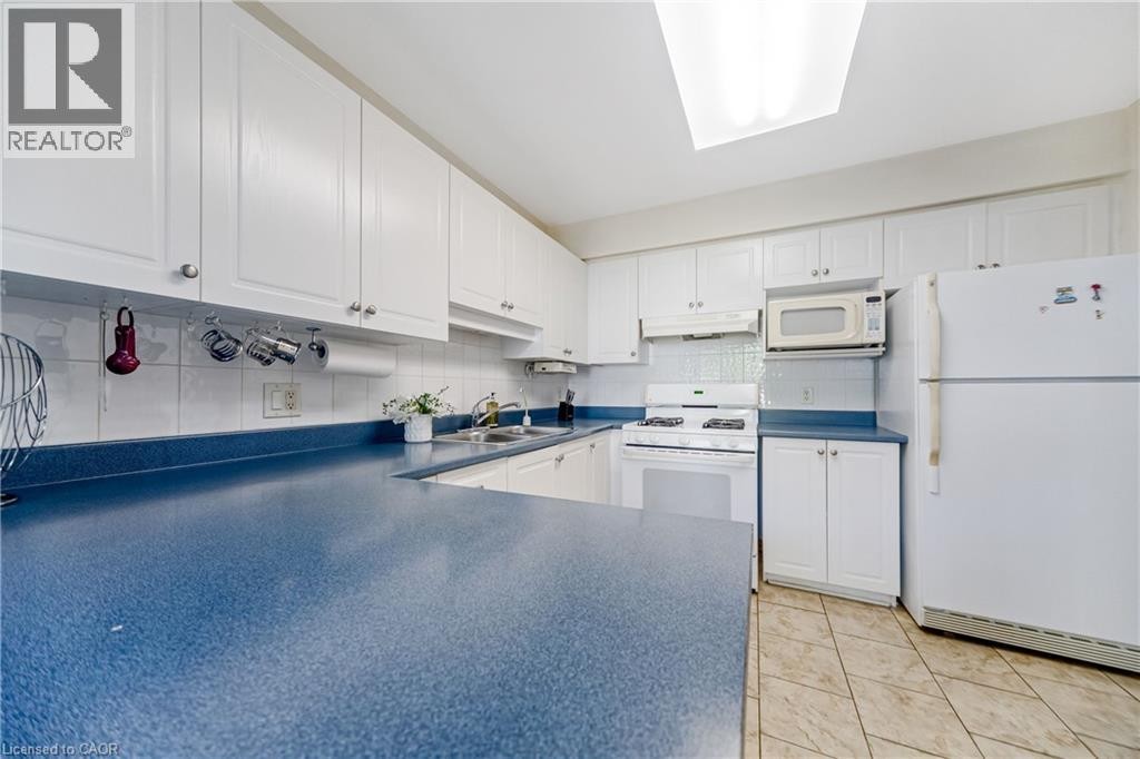 Kitchen featuring white cabinetry, blue countertops, white tile backsplash, and a skylight - 82 Milner Downs Crescent, Ottawa, ON