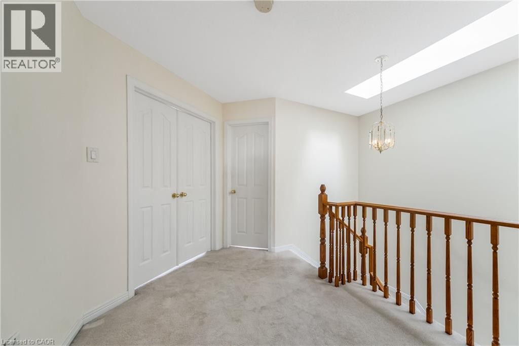Wood-tone staircase railing with white spindles, skylight, and a decorative chandelier - 82 Milner Downs Crescent, Ottawa, ON