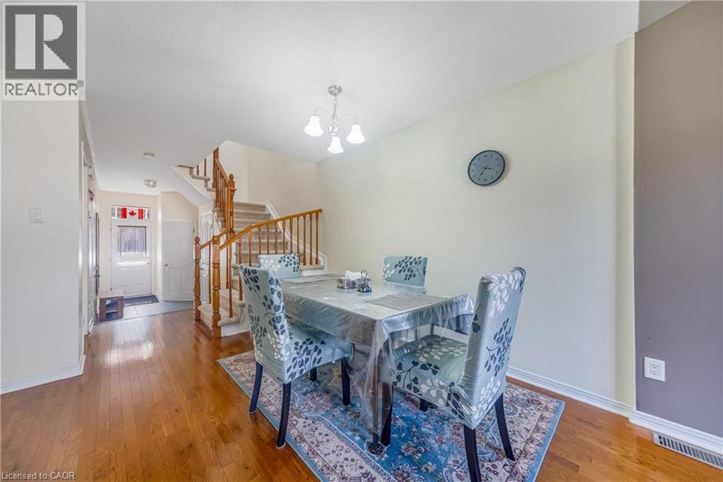 Hardwood flooring, painted walls, a built-in staircase with wood railings, and an overhead light fixture - 82 Milner Downs Crescent, Ottawa, ON