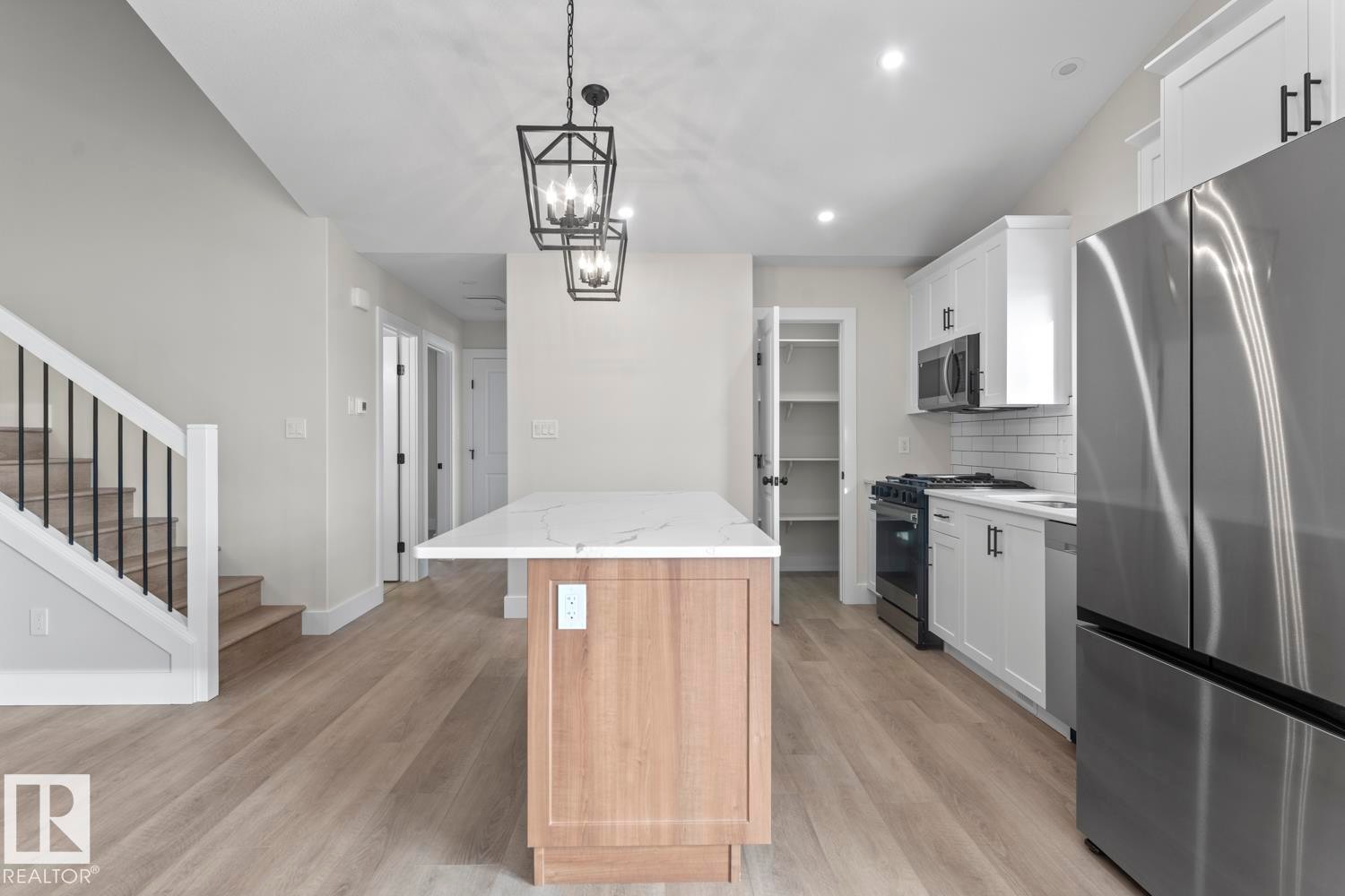 The property features a bright kitchen with white cabinetry, stainless steel appliances, and a central island with a white countertop - 807 Schooner Drive, Cold Lake, AB - Indoor Photo Showing Kitchen With Stainless Steel Kitchen