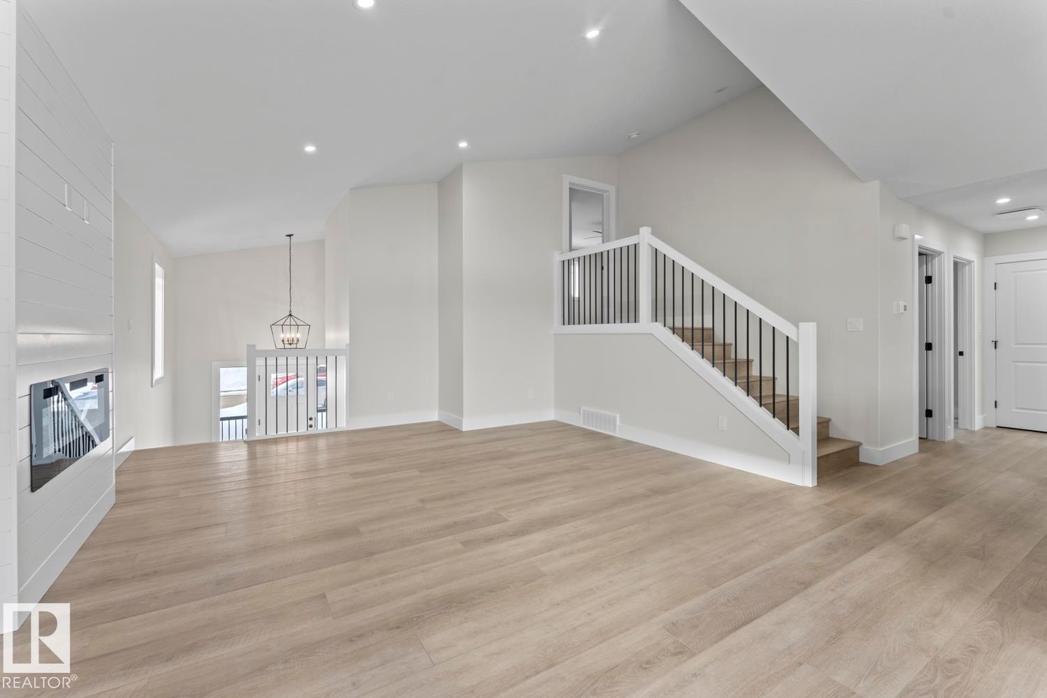 The property features light-toned flooring, a fireplace with a visible firebox, and a staircase with light-toned treads and dark-toned spindles - 807 Schooner Drive, Cold Lake, AB - Indoor Photo Showing Other Room