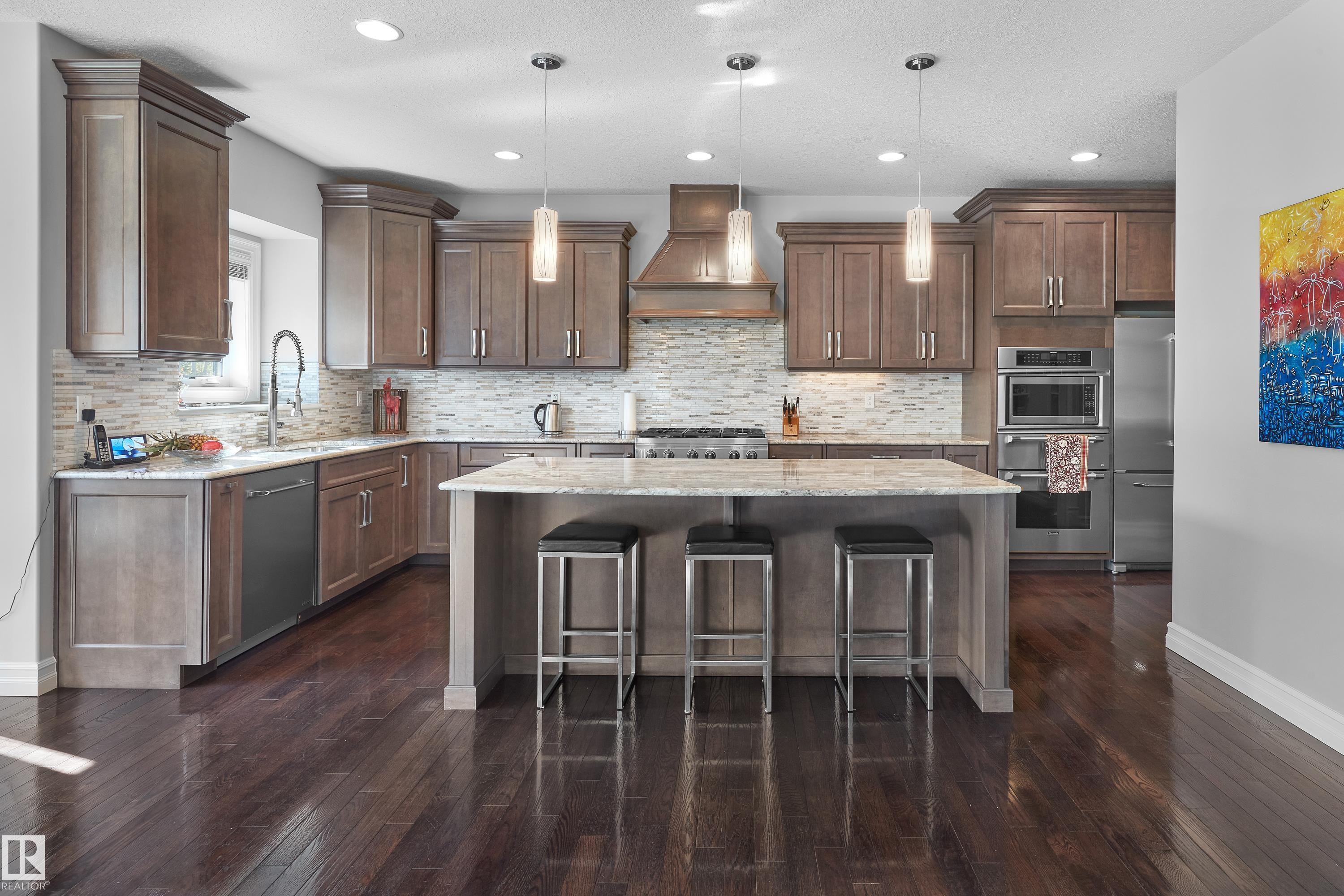 Kitchen with custom range hood, stainless steel appliances, a kitchen island, a kitchen bar, and tasteful backsplash - 4111 Westcliff Heath Heath, Edmonton, AB - Indoor Photo Showing Kitchen With Upgraded Kitchen