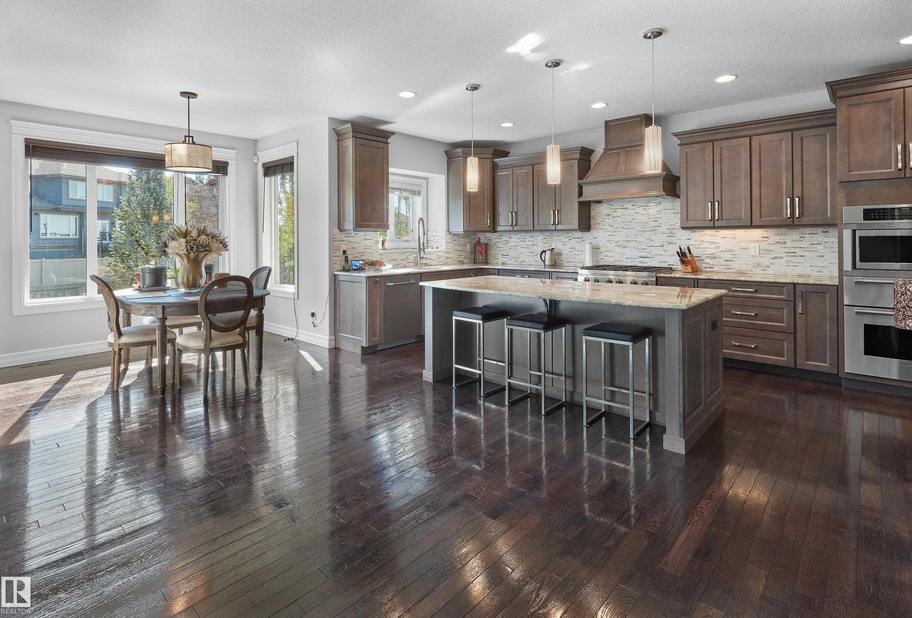 Kitchen with dark wood-type flooring, custom exhaust hood, decorative backsplash, a kitchen island, and a kitchen bar - 4111 Westcliff Heath Heath, Edmonton, AB - Indoor