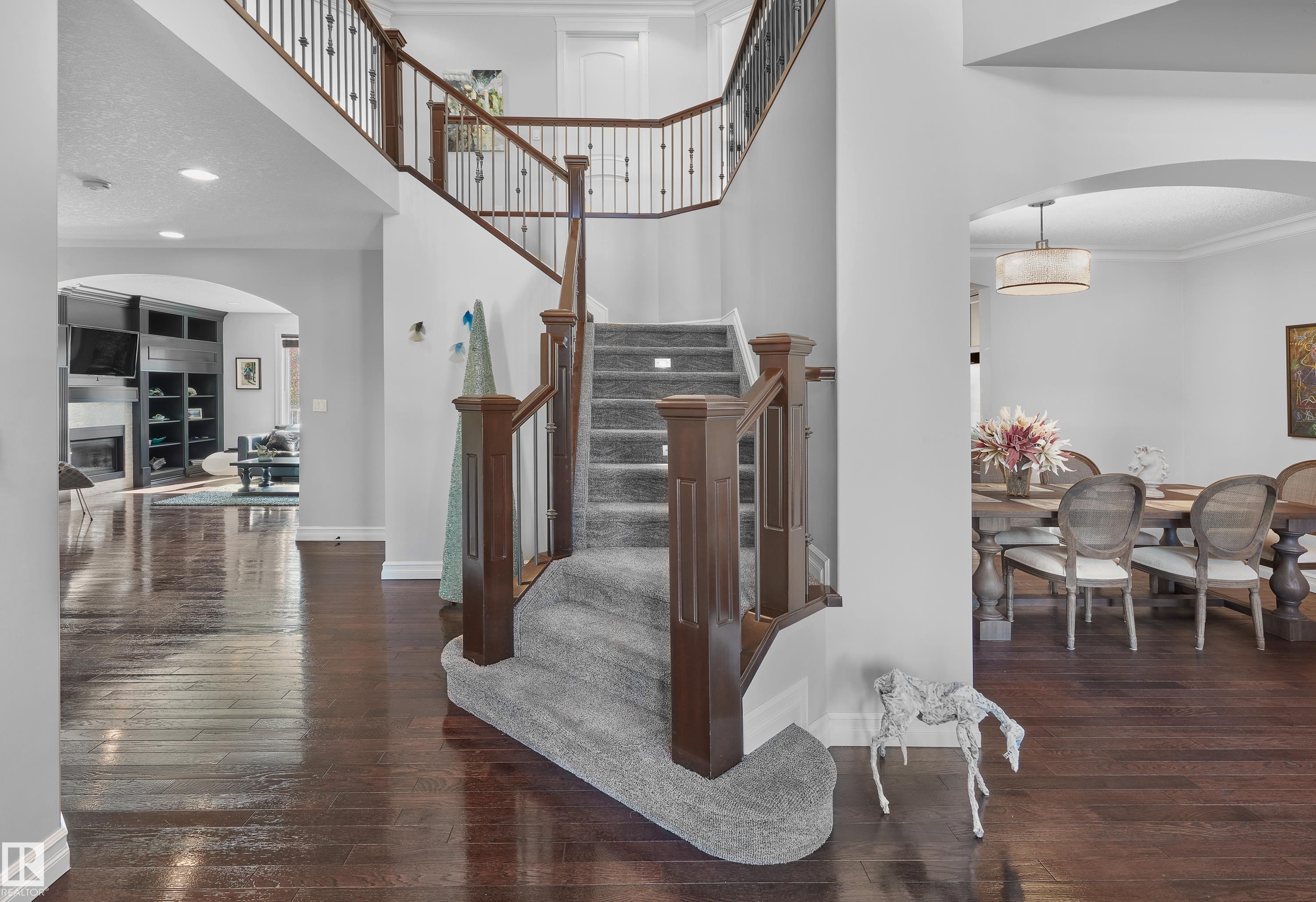 Stairway with arched walkways, hardwood / wood-style flooring, a glass covered fireplace, ornamental molding, and a high ceiling - 4111 Westcliff Heath Heath, Edmonton, AB - Indoor Photo Showing Other Room