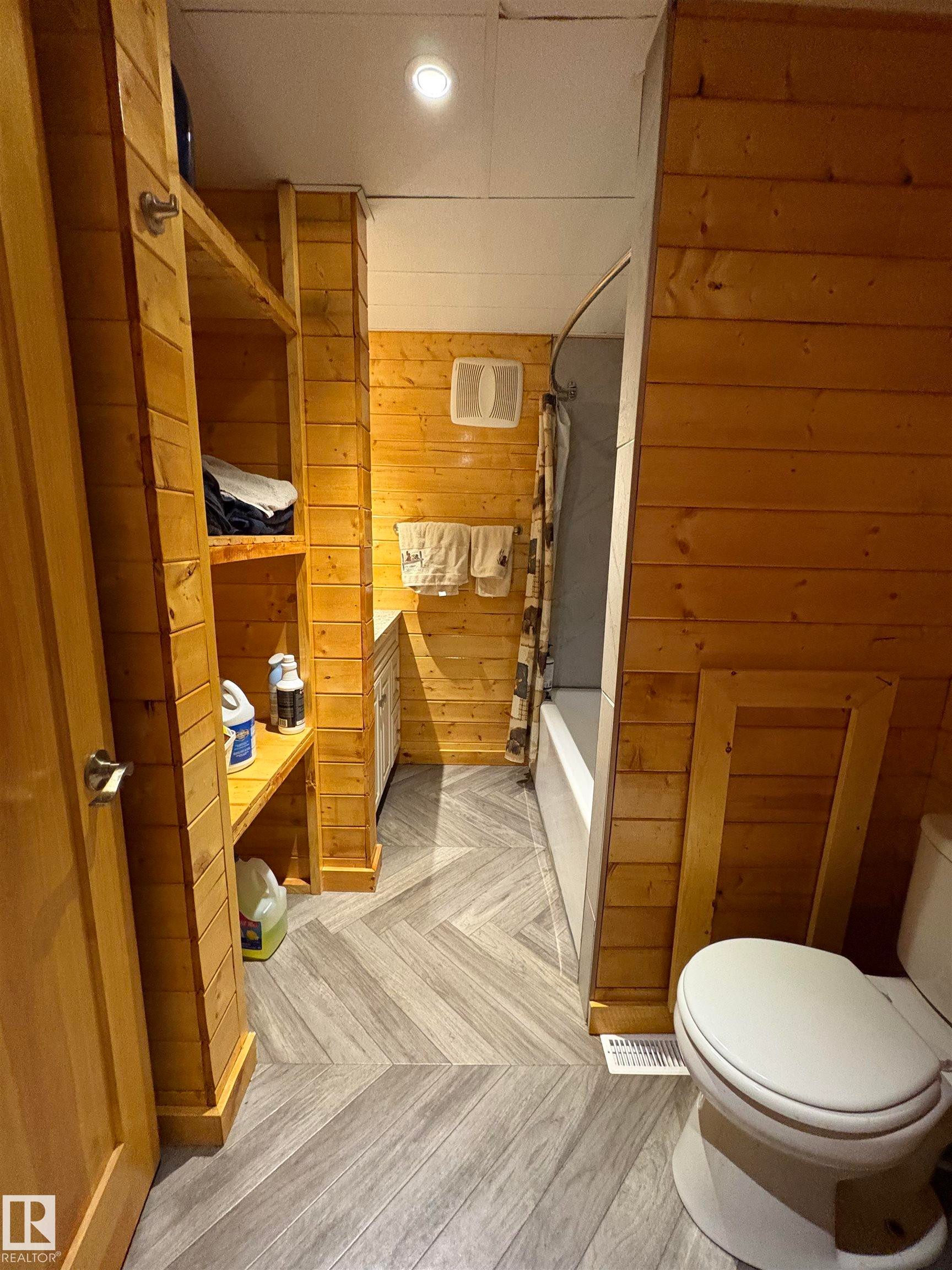 Full bath featuring wood walls, and shower / bath combo - B58018 Hiway 29, Rural St. Paul County, AB - Indoor Photo Showing Bathroom