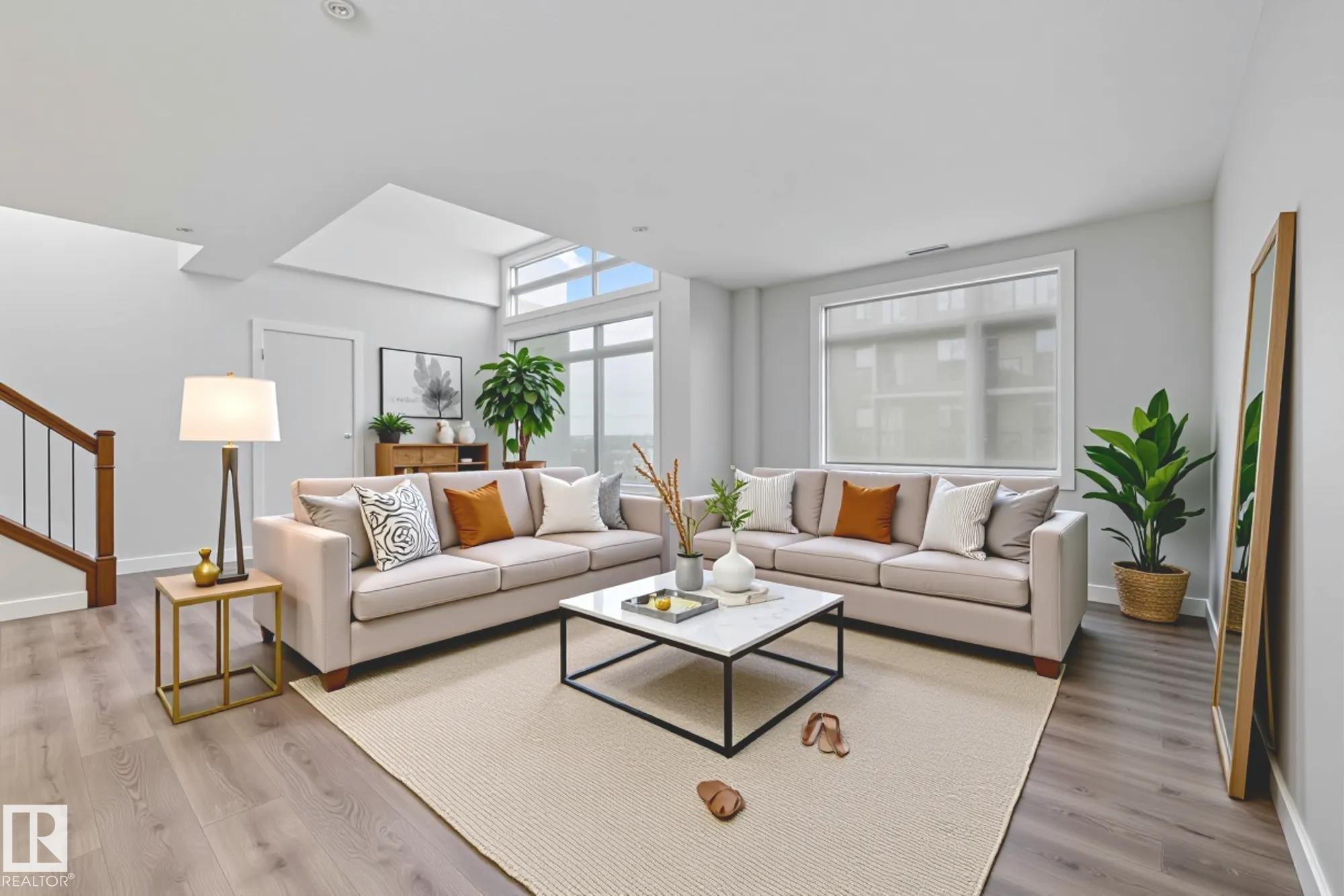 Living area with light wood-style floors and stairs - 810 5151 Windermere Boulevard, Edmonton, AB - Indoor Photo Showing Living Room