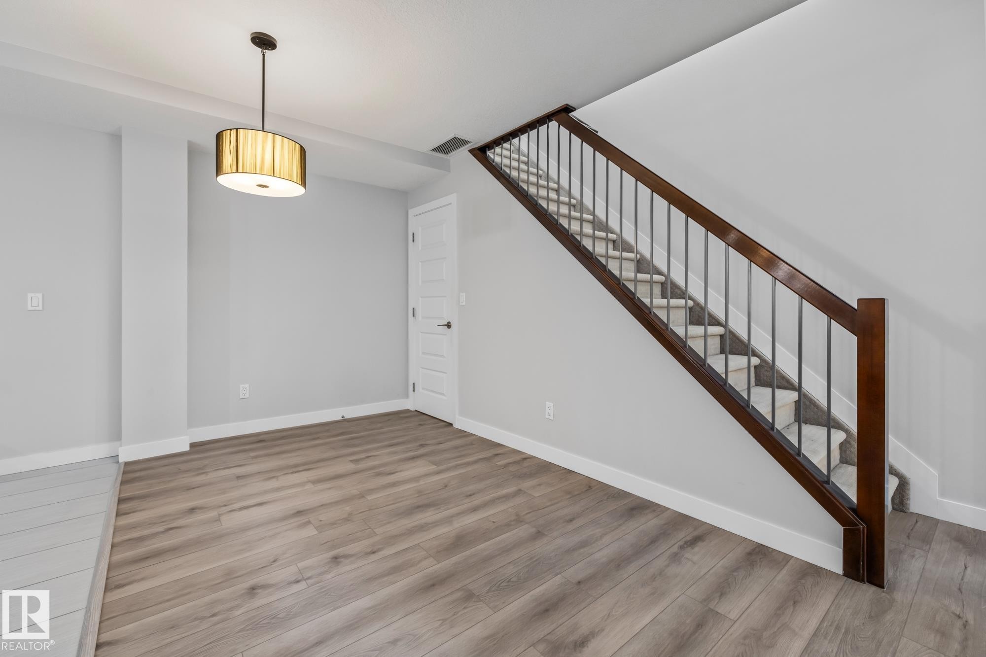 Unfurnished living room with wood finished floors and stairs - 810 5151 Windermere Boulevard, Edmonton, AB - Indoor Photo Showing Other Room